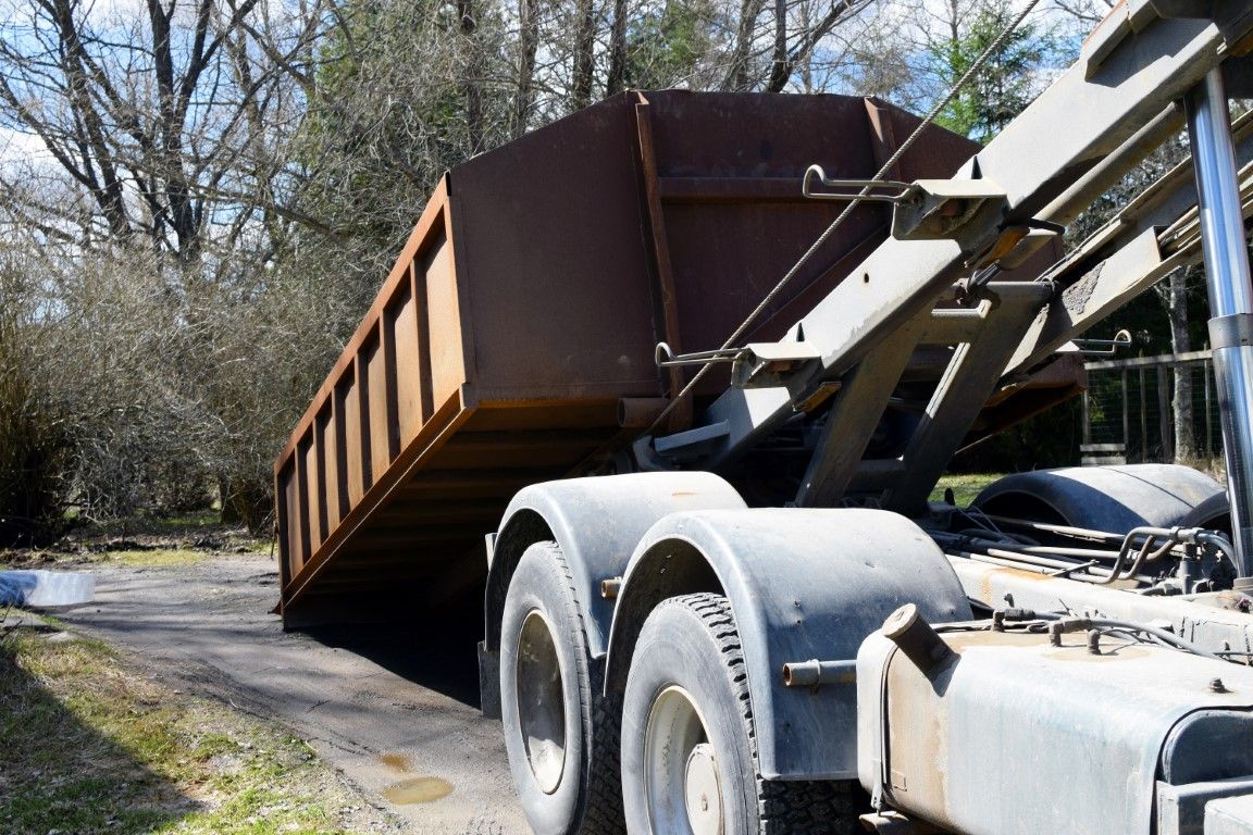 Rusted roll-off container loaded on the back of a hook-lift truck